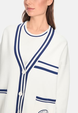 White cardigan with navy stripes, featuring a V-neck, two front pockets, and a button closure. Soft knit material with a relaxed fit.