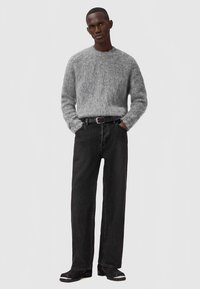 Pelēks pūkains džemperis, melnas taisnas bikses un melnas kurpes ar sudraba akcentu. Vienkāršs dizains, mīksta tekstūra un brīvs siluets.