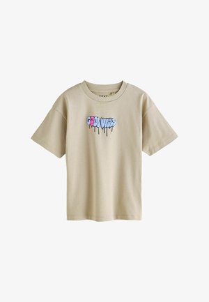 T-shirt beige à manches courtes avec col rond côtelé et texte coloré style graffiti « COOL VIBES » avec effet de peinture qui coule à l’avant.