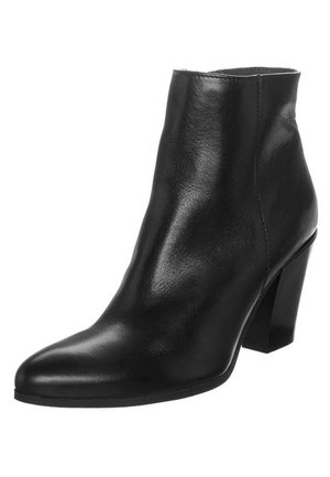 Bottine en cuir noir à bout pointu et talon mi-haut épais sur fond blanc.