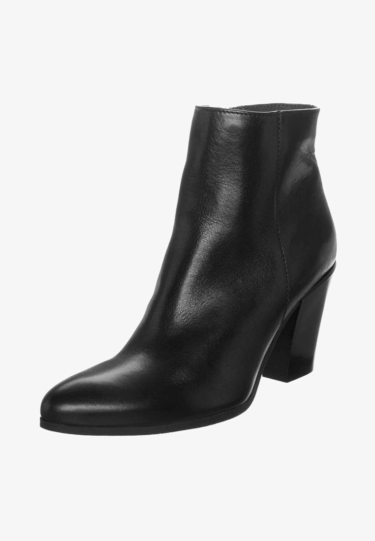Bottine en cuir noir à bout pointu et talon mi-haut épais sur fond blanc.