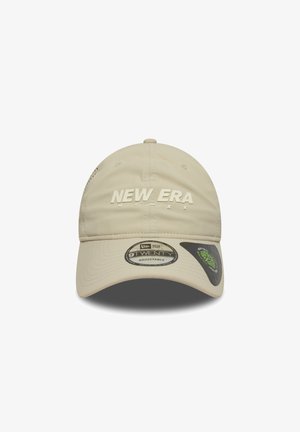 Beige adjustable cap with "NEW ERA" logo in raised lettering. Features a smooth fabric texture and rounded visor design.