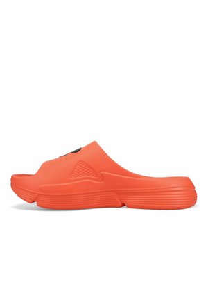 Orange slip-on-skor med texturerad ovansida, rundad tå och räfflad sula. Har ventilationshål och en slät yta.