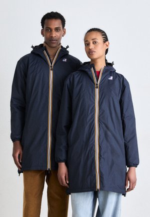 Les vestes à capuche bleu marine sont dotées d'une fermeture éclaire à l'avant avec des rayures jaunes et blanches, des poignets élastiques et une coupe décontractée. Les modèles portent des pantalons contrastants.