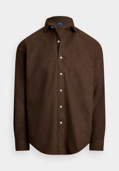 Pruun pika varrukaga nööpidega särk klassikalise kraega, millel on vasakul rinnal peenelt broderitud logo.