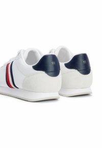 Sneakers bianche con tomaia in mesh, dettagli in pelle blu navy sul tallone, e strisce rosse e blu navy lungo il lato, con un pannello in suede grigio sul tallone.