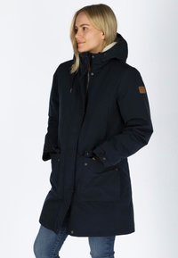 Parka blu navy con cappuccio, chiusura con bottoni a pressione e zip, due tasche frontali e fodera testurizzata. Dettaglio in pelle sulla manica.
