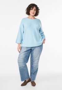 Maglione lavorato a maglia azzurro chiaro con scollatura rotonda, costa spessa e fit morbido. Abbinato a pantaloni in denim chiaro oversize con dettagli delle cuciture.