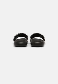 Black slide sandals with a textured footbed and contrasting patterned strap. Round open toe and backless design for easy wear.