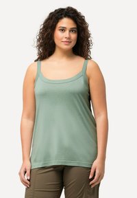 Light green sleeveless top in soft, breathable fabric with a square neckline and wide straps, paired with olive green pants.