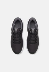 Black athletic shoes with a textured mesh upper, grey accents, and white soles. Features include a lace-up design and cushioned insoles.