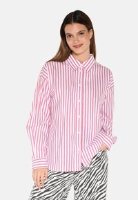 White button-up shirt with red vertical stripes, featuring a collar and long sleeves, paired with zebra-striped pants. Smooth cotton texture.