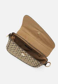 Beige mønstret clutch taske med guldknaplukning og ring. Indvendigt foret med beige stof og inkluderer en lynlåslomme til organisering.