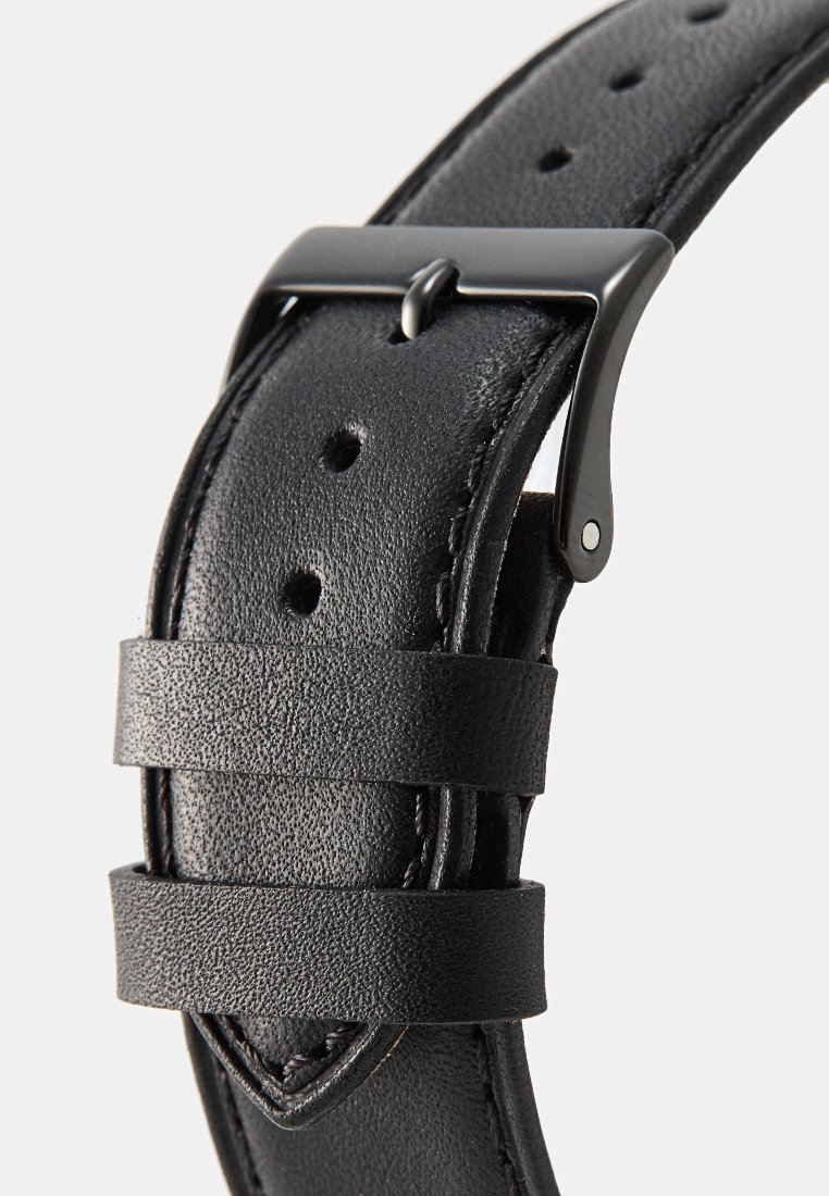 Correa de reloj de cuero negro con superficie texturizada, hebilla de metal en tono plateado y múltiples agujeros de ajuste para personalizar el tamaño.