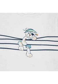 Witte T-shirt met een cartoonbeer met een ooglapje, bandana en shorts, leunend op marineblauwe horizontale strepen. Zacht materiaal.