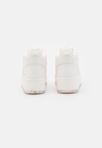 Białe sneakersy o teksturowanym wykończeniu, z wysokim krojem i kolorową, nakrapianą podeszwą. Minimalistyczne akcenty bez widocznych elementów metalowych.