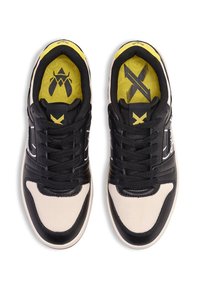 Svart- och beige sneakers med övre del av nät, texturerad krämbeläggning på tån, gul innersula med grafik och svarta snören.