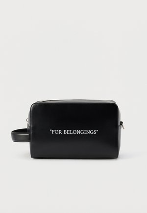 Black rectangular toiletry bag with side handle and white text "FOR BELONGINGS" on front, set against plain light background.