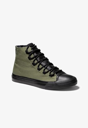 Wysokie sneakersy z oliwkowo zielonymi materiałowymi bokami, czarnym gumowym noskiem, podeszwą, językiem i grubymi czarnymi sznurowadłami na białym tle.