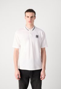Witte polo met een twee-kleurige kraag en zwart geborduurd logo op de borst. Gemaakt van zachte stof met korte mouwen en een klassieke pasvorm.