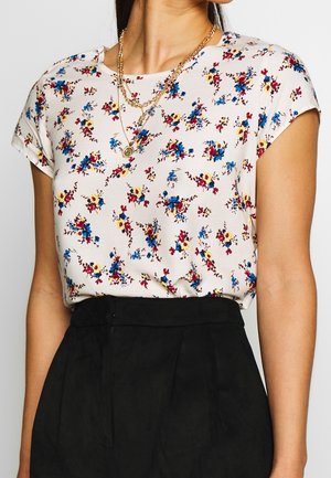 Korte mouw bloemenblouse van lichtgewicht stof. Heeft een roze basis met blauwe, gele en rode bloemenpatronen. Rechte zoom, ronde hals.