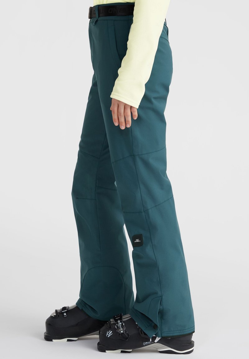 Türkise Schneehosen mit verstärkten Knien; verstellbarer Bund; schlanker Schnitt; passende Schneestiefel mit schwarzem Zubehör und Schnalle.
