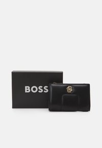 Portefeuille en cuir noir avec une surface texturée et un accent logo en ton doré. Présenté à côté d'une boîte noire avec "BOSS" en lettres argentées.
