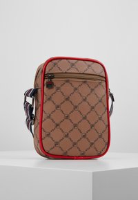 Sac en tissu marron avec des bordures rouges, présentant un motif de logo répétitif. Lanière ajustable multi-couleurs et poche zippée avant. Design rectangulaire.