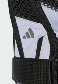 Férula atlética en blanco y negro con un diseño de malla, correas ajustables y una tela texturizada. Detalle del logotipo gris prominente en el costado.