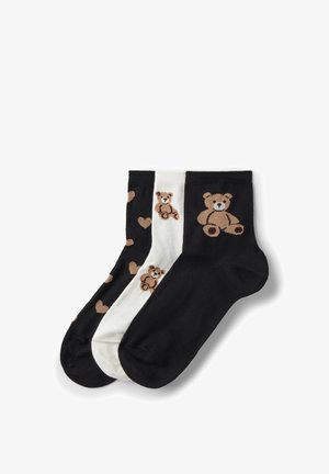 Drie enkelsokken in zwart en wit met bruine teddybeer- en hartpatronen, overlappend gerangschikt op een witte achtergrond.