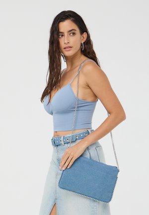 Borsa a tracolla in denim con dettagli in metallo argentato, forma rettangolare e tracolla a catena. Il colore azzurro chiaro si abbina perfettamente a un outfit casual.