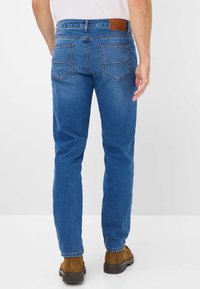 Blauwe denim jeans met een slim fit, voorzien van achterzakken, een bruine leren tailleband detail en lichte vervaging op de dijen.