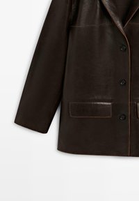 Braune Lederjacke mit Reverskragen, Knopfverschluss und zwei vorderen Taschen mit kontrastierenden Nähten an den Kanten.