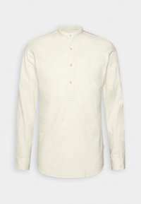 Camicia a maniche lunghe in bianco sporco, realizzata in tessuto testurizzato. Collo alla coreana con tre bottoni nella parte anteriore e orlo dritto.