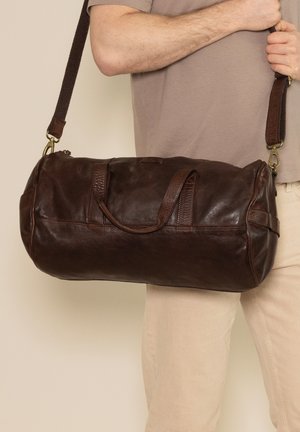 Brown leather duffel bag with a round shape, dual top handles, and an adjustable shoulder strap, featuring a textured finish and gold hardware accents.