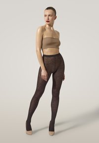 Leopardmönstrade strumpbyxor med ett svart och brunt m önster, tillverkade av genomskinligt material. Matchas med en naken strapless topp och neutrala klackar.