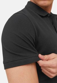 Schwarzes Poloshirt aus strukturiertem Stoff, mit Kragen und kurzen Ärmeln, ribbelte Bündchen und einem Knopfverschluss am Hals.