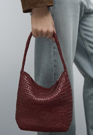 Vävd bordauxfärgad handväska med en böjd form, en texturerad yta och ett kort, flätat handtag, med en dragkedjeslutning på toppen.