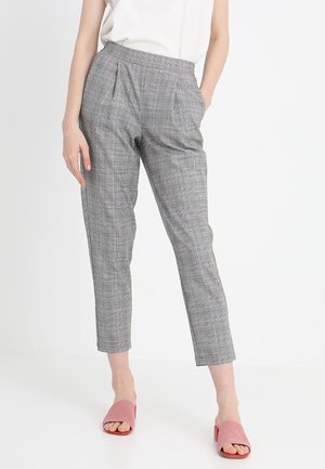Pantalons gris à carreaux avec une taille haute, des plis à l'avant et des jambes fuselées, associés à des sandales roses à enfiler.