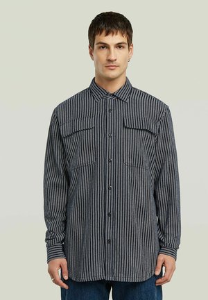 Camicia a maniche lunghe con bottoni, a righe verticali blu navy e bianche, due tasche sul petto e colletto a punta, realizzata in tessuto strutturato.