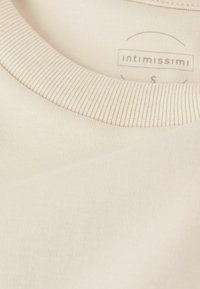 Beige, žebrované bavlněné tričko s kulatým výstřihem. Štítek uvádí "intimissimi," velikost "S." Hladký povrch, čisté švy, minimalistický design.