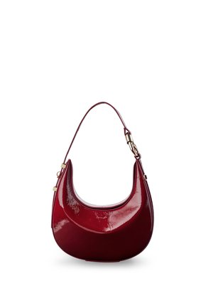 Glänzende dunkelrote halbmondförmige Handtasche mit kurzem Riemen und goldfarbenen Beschlägen vor weißem Hintergrund.