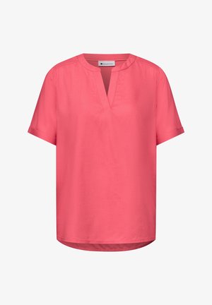 Korallinpunainen lyhythihainen paita, jossa on pyöreä halkiollinen pääntie ja hillitty ompelusomiste, sekä hieman kaareva helma.