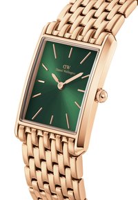 Gold-tone rectangular watch with a green sunburst dial, rose gold hands, and a woven metal bracelet. Features logo and textured crown.