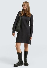 Vestido de punto gris oscuro con mangas largas, escote redondo y corte recto, combinado con botas negras hasta la rodilla. Diseño simple y texturizado.
