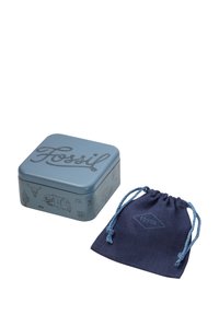 Boîte carrée en métal bleu avec un design en relief "Fossil" et divers graphiques. Accompagnée d'une pochette en tissu bleu marine avec cordons de serrage.