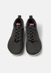 Zapatillas negras de cuero liso con punta redonda, que cuentan con cordones negros con detalles plateados y una pequeña pestaña para facilitar su uso.