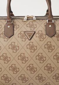 Sac à main marron à motif avec des accents en cuir, doté d'une fermeture zippée et d'une plaque de logo triangulaire. Surface texturée avec un motif en diamant.