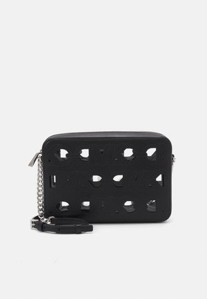 Black leather crossbody bag with cut-out logo pattern and silver chain. Smooth texture with a zip closure and detachable strap.