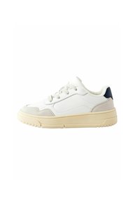 Witte sneaker met gestructureerd suede en gladde leren panelen, ronde neus, platte beige zool, en grijze en marineblauwe accenten aan de achterkant.